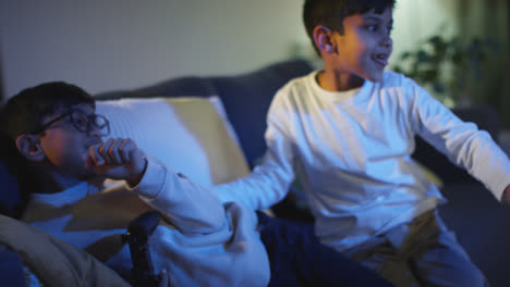 Two-Young-Boys-At-Home-Having-Fun-Playing-With-Computer-Games-Console-On-TV-Fighting-Over-Controllers-Late-At-Night-6